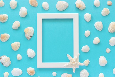 White frame with starfish on blue background and seashells. Creative Flat lay Top view Template for postcard, design Copy space for text.の写真素材