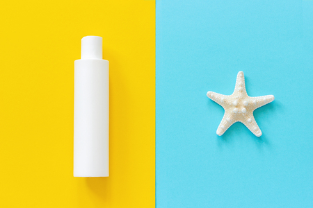 Sea starfish and white bottle of sunscreen on yellow and blue paper background. Mock up Template for lettering, text or your design Creative Top View.の写真素材