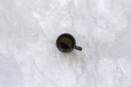 Black cup of coffee on marble table background. Top view Copy space Minimal style.の写真素材