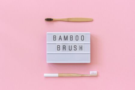 Two natural eco-friendly bamboo brushes with white and black bristles and lightbox text Bamboo brush on paper pink background. Top view Flat lay Template Conceptの写真素材