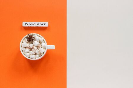 Autumn composition. Wooden calendar month November and cup of cocoa with marshmallows on orange beige background. Top view Flat lay Copy space Concept Hello November.の写真素材
