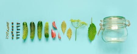 Pickled cucumbers. Ingredients for marinated gherkins and glass jar on blue background. Concept culinary recipe preservation of vegetables in harvest season. Creative flat lay Top view Banner.の写真素材