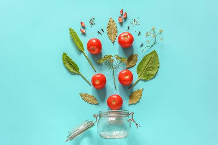 Pickled tomatoes. Flying ingredients for marinated tomatoes and glass jar on blue background. Concept culinary recipe preservation of vegetables in harvest season. Creative flat lay Top view.の写真素材