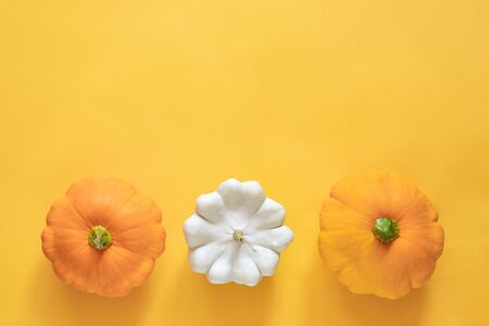Three fresh yellow and white pattypan squash on yellow background with copy space. Top view Flat lay...