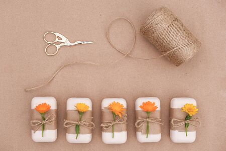 Handmade natural soap set decorated with craft paper, orange calendula flowers, skein of twine and...