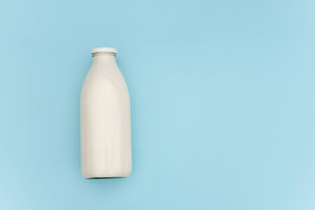 Milk in glass bottle on blue background with copy space. Flat lay Top view.の写真素材