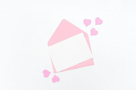 Love Letter. Pink envelope with white blank card and hearts on white background. Top view Flat lay...