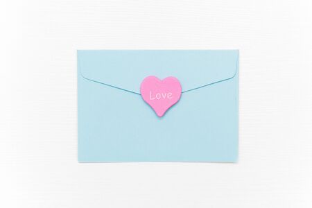 Love Letter. Blue closed envelope and pink heart with text LOVE on white background. Top view Flat...