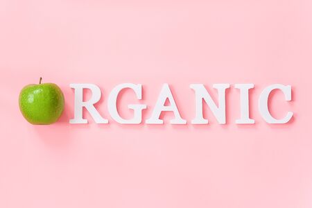 Natural green apple and text Organic from volume white letters on pink background. Creative concept Organic natural fruits food Top view Flat lay Copy space.の写真素材
