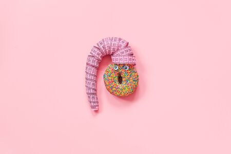 Abstract funny face of woman from donut with eyes and hair from centimeter tape on pink background....