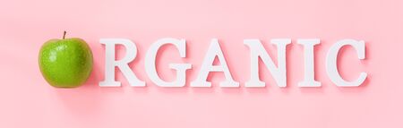 Natural green apple and text Organic from volume white letters on pink background. Creative concept Organic natural fruits food Top view Flat lay Banner.の写真素材