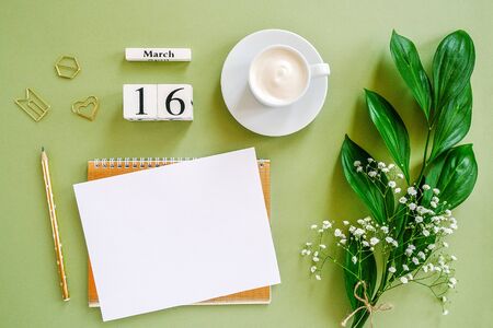 Wooden cubes calendar March 16. Notepad, cup of coffee, bouquet flowers on green background. Concept hello spring Creative Top view Flat lay Mock up.の写真素材
