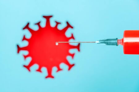 Syringe with vaccine drug and abstract red coronavirus, virus, bacteria, microbe on blue background. Concept vaccination and infectious diseases, pandemic Covid -19.の写真素材
