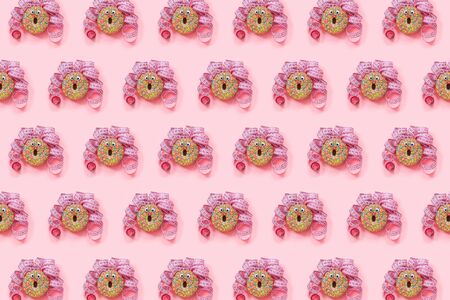 Donat pattern on pink background. Abstract funny face of woman from donut with eyes and hair from centimeter tape. Diet or unhealthy food concept Top view Flat lay.の写真素材