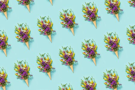Flower pattern. Bouquet field colored flowers in waffle ice cream cone on blue paper background...