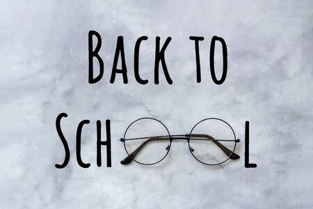 Back to school text and stylish black round eyeglasses spectacles on marble background. Concept...