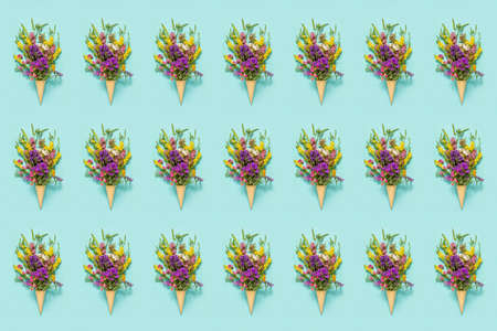 Flower pattern. Bouquet field colored flowers in waffle ice cream cone on blue paper background...