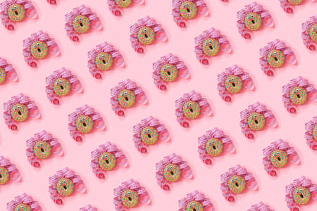 Donat pattern on pink background. Abstract funny face of woman from donut with eyes and hair from centimeter tape. Diet or unhealthy food concept Top view Flat lay.の写真素材