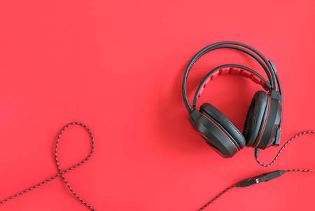 Black headphones on red background. Concept listening to audio material and abstract, distance education. Top view copy space.の写真素材