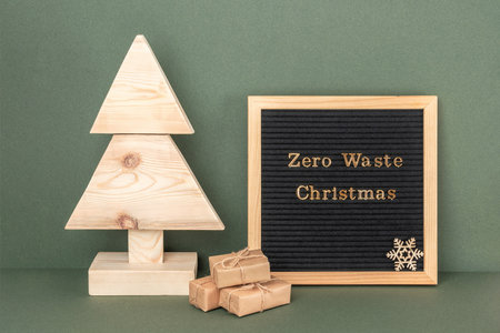 Zero Waste Christmas text on letter board. Homemade wooden Christmas tree and gifts on green background. Concept xmas zero waste, eco-friendly. Front view.の写真素材