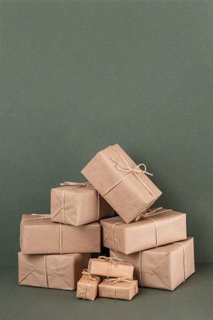 Lots of gifts boxes in craft paper with twine on green background. Holiday concept. Front view.