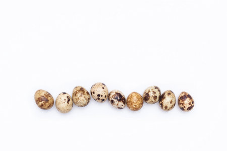 A row of quail eggs on a white background. Top view Flat lay Copy space.の写真素材