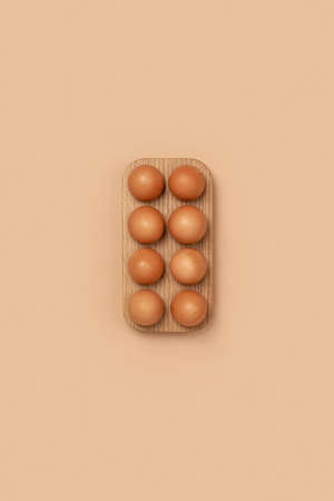 Natural organic eggs in wooden egg box on beige background. Compositions in monochrome colors. Zero...