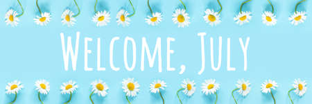 Welcome, July text in frame from chamomile flowers on blue background. Concept Hello summer time. Banner.の写真素材