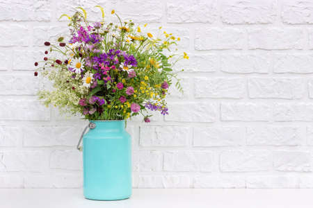 Bouquet of bright flowers in tin can vase on background white brick wall. Template for postcard. Concept Women's day, Mothers Day, Hello summer or Hello spring.の写真素材