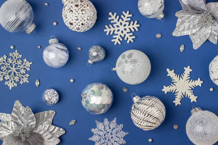 Holiday pattern made silver and white shiny christmas decorations on blue background. Happy Christmas, Xmas and New Year concept. Top view, Flat lay.の写真素材