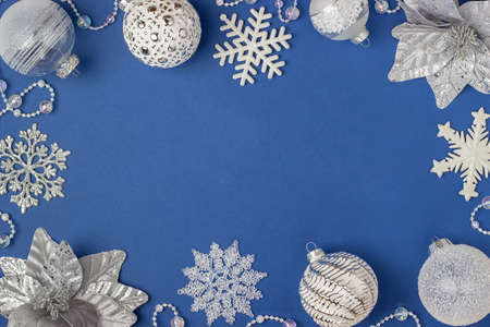 Holiday frame made silver and white shiny christmas decorations on blue background. Happy Christmas, Xmas and New Year concept. Top view, Flat lay, Copy space.の写真素材
