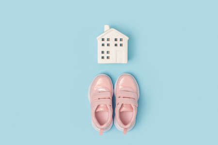 Pink sneakers and white ceramic house on a blue background. creative sport concept. Top view flat...
