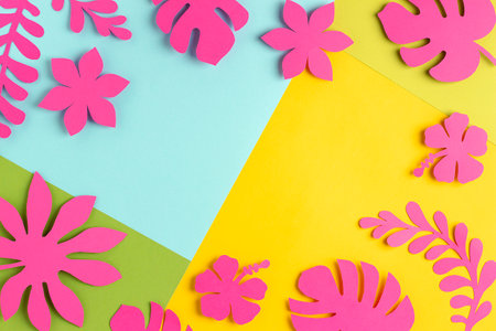 Trendy sunlight tropical frame made with bright pink paper flowers and leaves on blue yellow background, as backdrop or texture. Floral border for your design. paper art.の写真素材