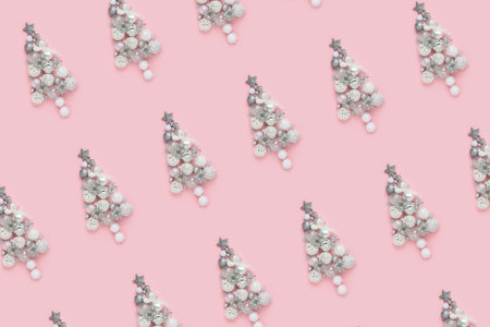 Holiday pattern made with creative Christmas trees from xmas baubles, decor in flat style on pink background. Merry Christmas and Happy New Year concept. Top view, flat lay.の写真素材