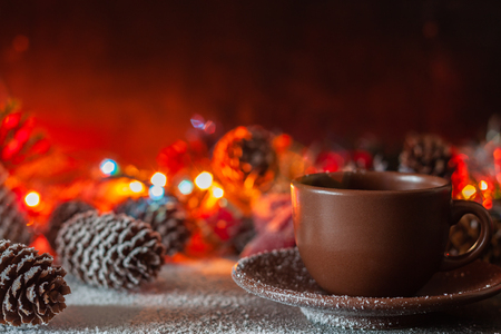 On the table is a cup of coffee on the background of New Year's garlandsの写真素材