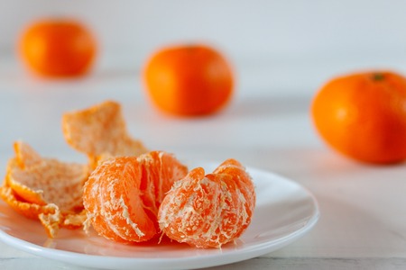On a white table in a dish is peeled mandarinの写真素材