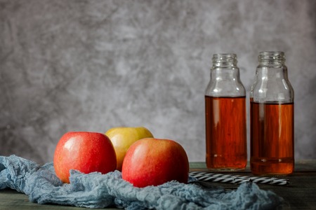 On the table are apples and freshly squeezed juice in a glass bottle