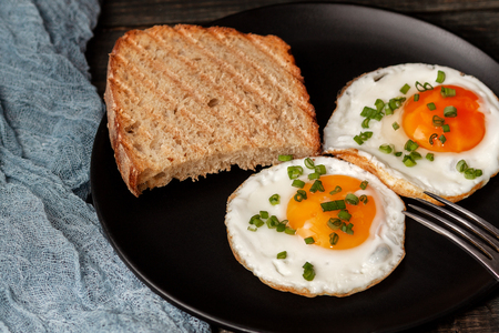 Fried egg on a black plate on a wooden black tableの写真素材