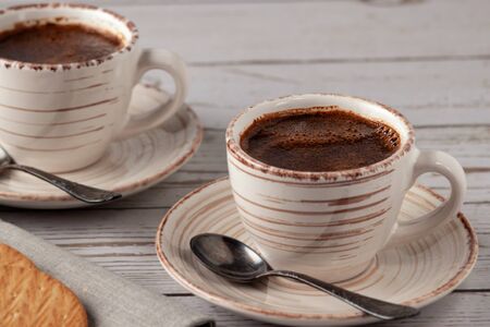 On an old white wooden table a cup of aromatic coffee.