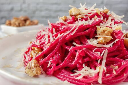 On a light background spaghetti with beetroot pesto sauce, walnuts and parmesanの写真素材
