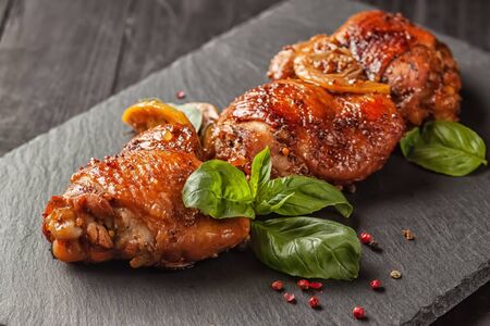 On a wooden table, chicken thighs and basil in a black cast-iron skilletの写真素材