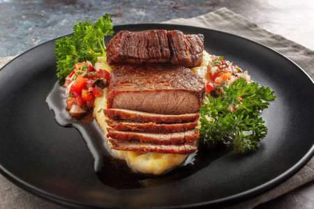 On a dish beef medallions with tomato salsa and cream polentaの写真素材