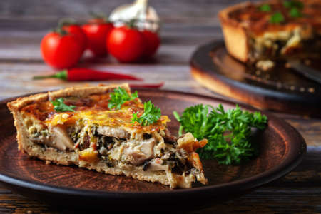 Traditional french quiche pie with chicken and mushroom on a wooden backgroundの写真素材