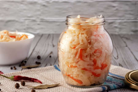 On a wooden table, sauerkraut with carrots and spices in a bowl. Horizontal top view, rustic styleの写真素材