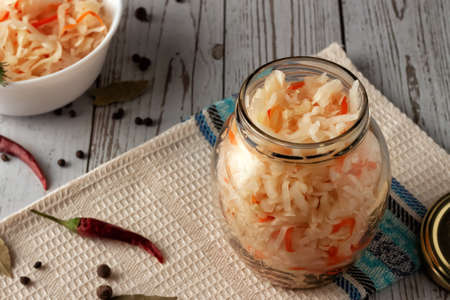On a wooden table, sauerkraut with carrots and spices in a bowl. Horizontal top view, rustic styleの写真素材