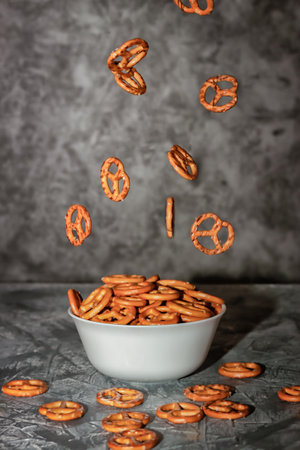 Food levitation. Small cookies in the form of pretzels falling into a clay bowlの写真素材