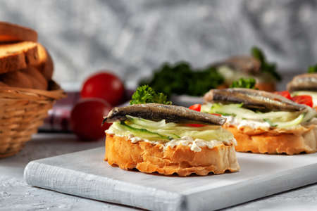 Smoked sprat sandwich - fish, fresh cucumber and tomato. Sprat sandwiches on toasted slices of breadの写真素材