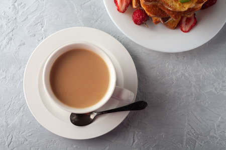 A cup of coffee with cream and French toast with cinnamon and strawberries. Morning breakfastの写真素材
