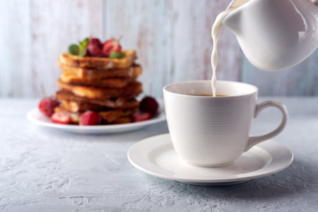 A cup of coffee with cream and French toast with cinnamon and strawberries. Morning breakfastの写真素材