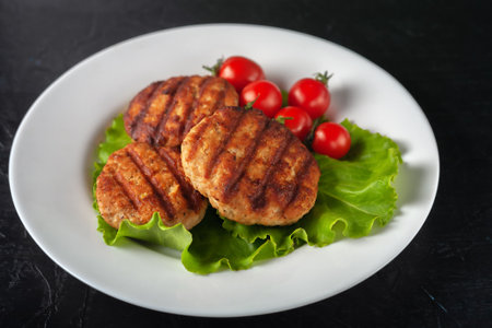 Fresh homemade cutlet with lettuce and tomatoes on a black background